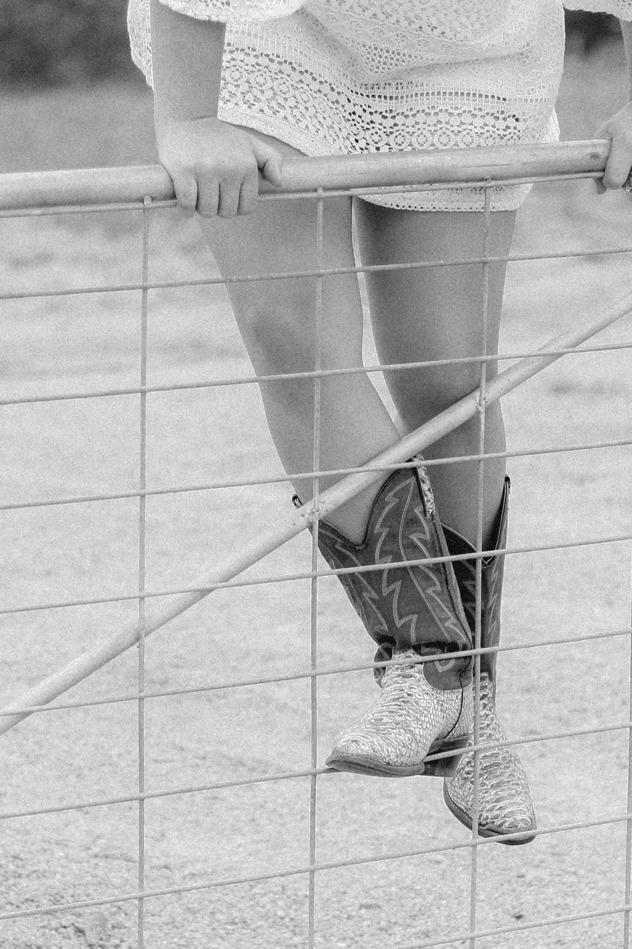 Gros plan sur les jambes d’une femme en bottes western, franchissant une barrière, symbole de passage