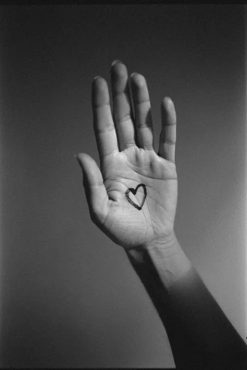 Main ouverte avec un cœur dessiné au creux de la paume, symbole d’amour transmis au-delà de la mort