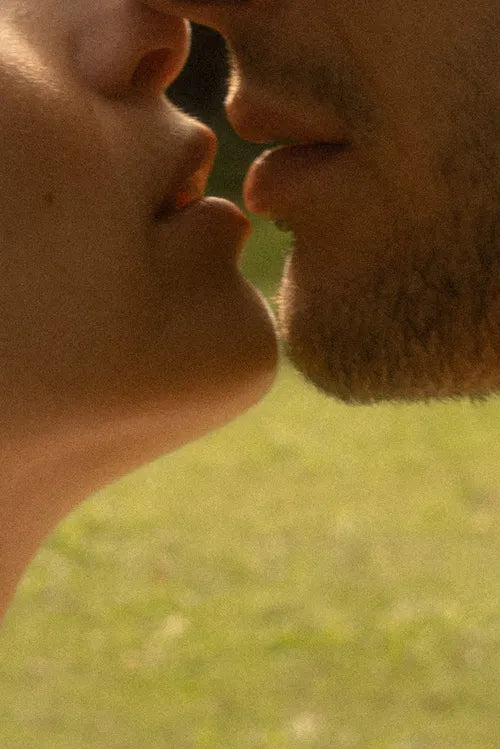 Zoom intime sur deux visages se rapprochant pour un baiser, représentant l’attraction et le désir.