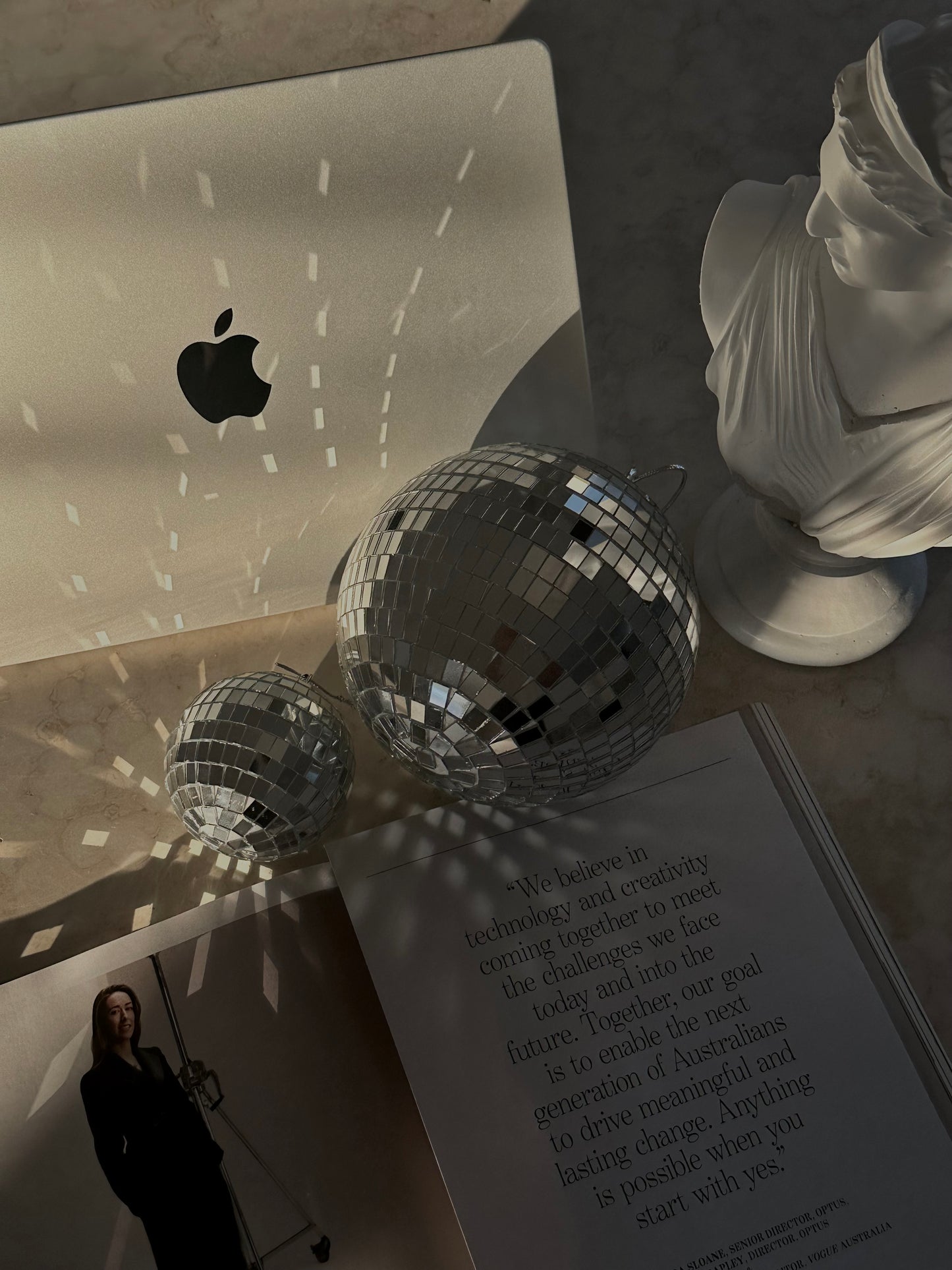 Rayonnement lumineux sur un ordinateur Apple, sphères miroir et buste blanc – énergie créative et ouverture à l’abondance financière