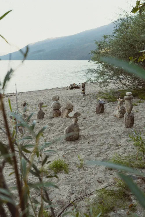 Petits cairns de pierre alignés sur une plage paisible au bord d’un lac