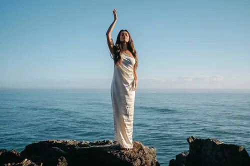 Femme lumineuse au bord de l'ocean, après un soin de nettoyage energetique
