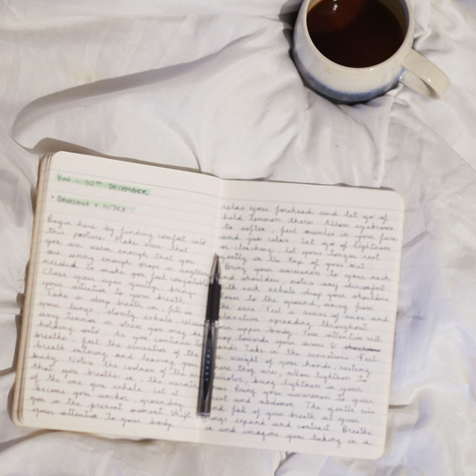 Moment de recentrage, carnet et tasse de café posés sur un lit blanc, ambiance de guidance intuitive.