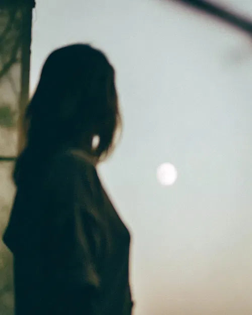 Femme en quête de réponses sous la lune, intuition et guidance par le pendule