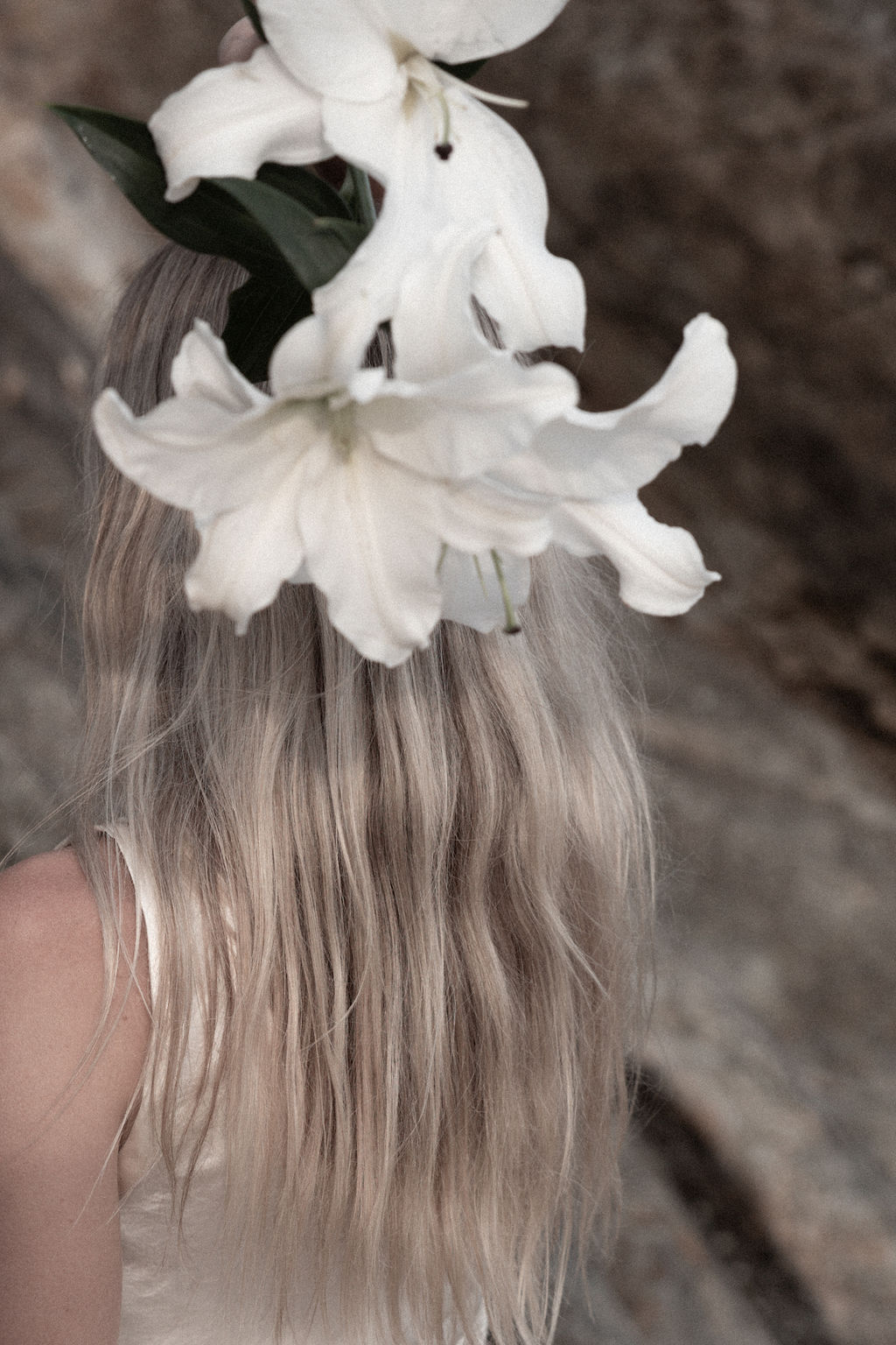 Femme blonde de dos avec un lys blanc, symbole de pureté et de réceptivité vibratoire dans un rituel d’amour. Mariage