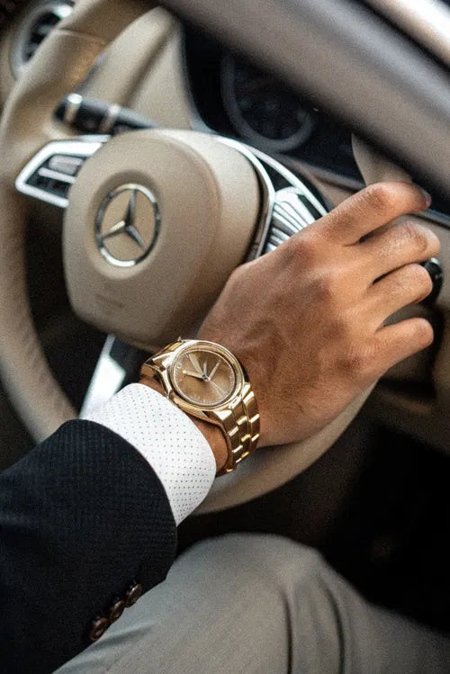 Soin énergétique pour attirer l’abondance – main d’un homme au volant d’une voiture de luxe, avec montre prestigieuse