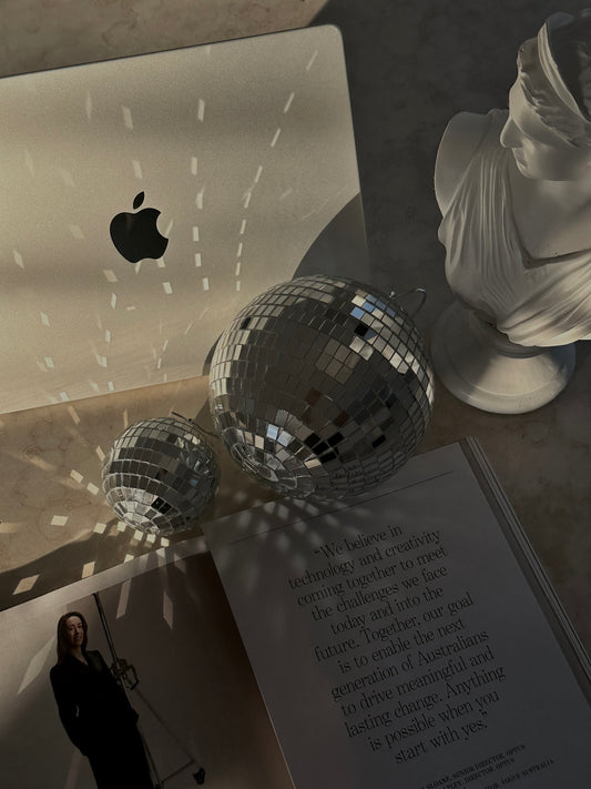 Rayonnement lumineux sur un ordinateur Apple, sphères miroir et buste blanc – énergie créative et ouverture à l’abondance financière